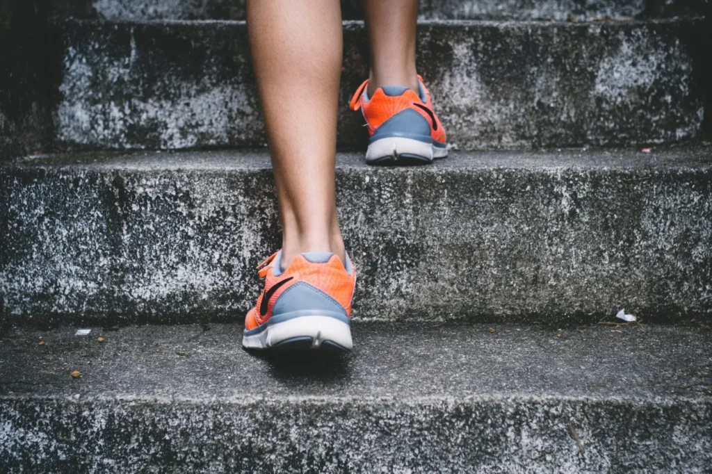 Legs climbing concrete stairs in orange running shoes