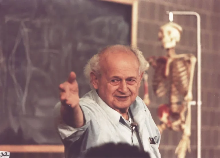 Moshe Feldenkrais teaching in front of a blackboard and skeleton